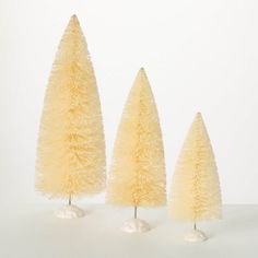 three small yellow trees are standing next to each other on a white surface with one tree in the middle