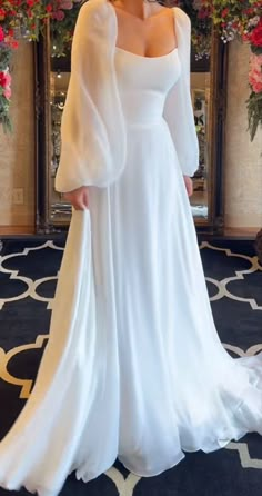 a woman in a white wedding dress posing for the camera with her hands on her hips