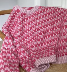 a pink and white blanket sitting on top of a wooden chair