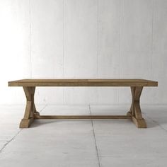 a wooden table sitting on top of a white floor next to a wall with a plant in it