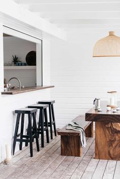 a kitchen with wooden floors and stools next to a counter top in front of a window