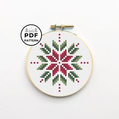 a cross stitch kit with a red and green snowflake