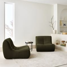 a living room with two green chairs and a coffee table on the floor in front of a white wall