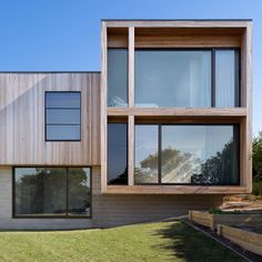 a house that is made out of wood and has large windows on the side of it