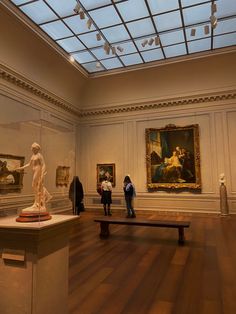 people looking at paintings in an art museum with skylights on the ceiling and wooden floors