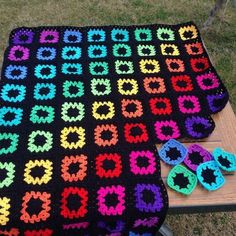 a crocheted blanket and pair of slippers on a bench