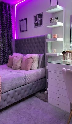 a bed room with a neatly made bed next to a desk and purple lighting on the walls