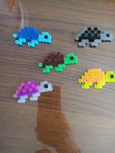 several different colored beads sitting on top of a wooden table next to a person's hand