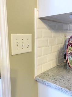 a kitchen counter with a plate on it and a light switch in the wall behind it