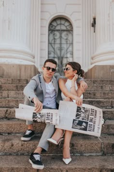 a man and woman are sitting on the steps with newspapers in front of their feet