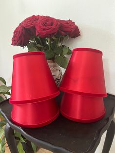 two red lamps sitting on top of a table next to a vase with roses in it