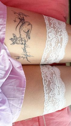 two women with tattoos on their legs and one has a white lace garter around her waist