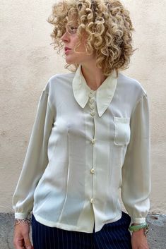 Vintage Matsuda White Shirt With Asymmetrical Collar in wonderful condition. This semi-sheer creamy button down is elegant with vintage flair. A timeless beauty. Comfortable and versatile. Made in Japan. dry clean only. 100% polyester. Best fits size S/M. Approx Measurements: Underarm to underarm: 17" across Length: 25" Elegant Shirt With Button Closure For Daywear, Elegant Silk Shirt For Daywear, Elegant Shirt With Buttons For Daywear, Elegant Beige Shirt For Workwear, White Fitted Silk Shirt, Silk Cream Top For Office, Elegant White Blouse With Fold Down Collar, Elegant Beige Shirt For Work, Classic Beige Formal Tops