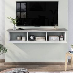 a flat screen tv sitting on top of a white shelf next to a wooden table