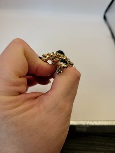 a hand holding a gold ring with black stones