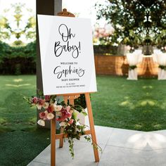 a sign that says oh baby welcomes to everyone on it and flowers in the foreground