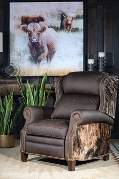 a living room with a cow print on the wall and a leather recliner chair