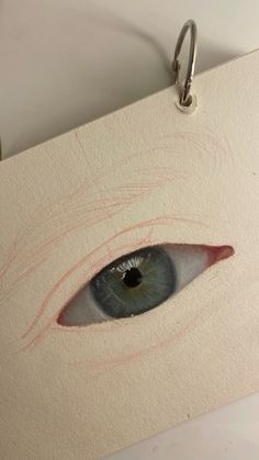 a drawing of an eye is shown in the middle of a piece of paper with a hook on it