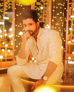 a man sitting on top of a table in front of a wall covered with lights