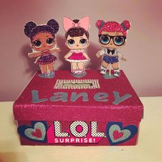 three little dolls sitting on top of a pink box with the word l o l surprise