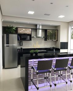 a modern kitchen with black counter tops and purple bar stools in front of an island