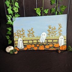 two white ghost pumpkins sitting in front of a fence