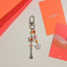 a keychain with charms attached to it sitting next to a pink card holder