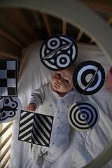 a baby laying in a crib surrounded by black and white magnets on the wall