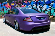 a purple car parked in front of a graffiti covered wall