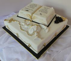 a cake decorated with two books on top of each other and gold trimmings