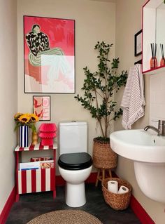 a white toilet sitting in a bathroom next to a sink and a potted plant