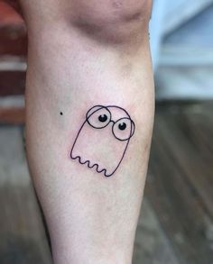 a small black and white tattoo on the leg of a person with an evil face