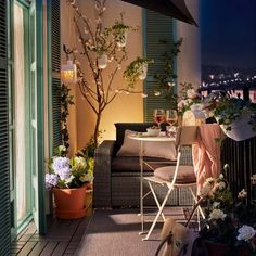 an outdoor patio area with wicker furniture and potted plants on the balcony at night