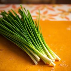 some green onions sitting on top of a yellow cutting board with sprouts sticking out of it