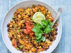 a white bowl filled with black beans, corn and cilantro on top of a blue table