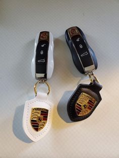 three different types of car key chains on a white surface with black and gold emblems