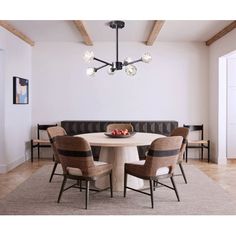 a dining table with four chairs around it in the middle of a living room area