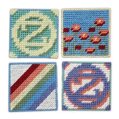 four square coasters with different designs and colors on each one, including the letter e