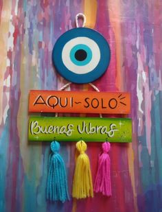 three tassels hanging from a wall with an evil eye on the sign above them