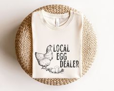 "Local Egg Dealer Shirt. This cute Easter Chicken design is the perfect tshirt for wearing this Easter. Buy it for yourself or give it as the perfect gift for teacher, mom or chicken loving mama.  Local Egg Dealer Shirt, Easter Shirt, Christian Easter Shirt, Happy Easter Shirt, Chicken shirt, Chicken Gifts for Farmer, Mama Easter Shirt ⭐️HOW TO ORDER��⭐️ Select your quantity of shirts in the specific colour/size and click \"ADD TO BASKET\"   Repeat as needed by returning to the listing button to a Easter Clothing, Dark Blue Sweatshirt, Chicken Design, Easter Chicken, Chicken Shirt, Chicken Gifts, Chicken Shirts, Teacher Mom, Gifts For Farmers