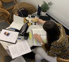 a woman sitting at a table with books and papers