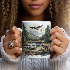 a woman holding a coffee mug with an image of a bear and camper on it