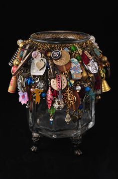 a glass container filled with lots of different types of jewelry on top of a black surface