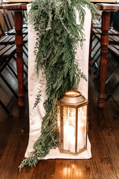 a candle is lit next to a green garland on a table with white linens