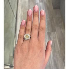 a woman's hand with a yellow and white diamond ring on her left hand