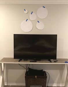 a flat screen tv sitting on top of a wooden table next to a basket and wall decoration