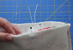 someone is stitching together fabric with pins and needles to make a pillow or cushion