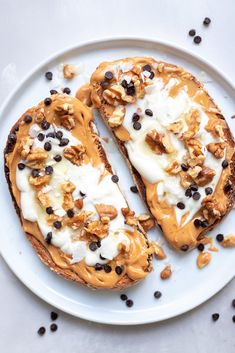 two pieces of toast with nuts and cream on it sitting on a plate next to coffee beans