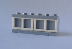 a white lego building with three windows and four candles on the top one is empty