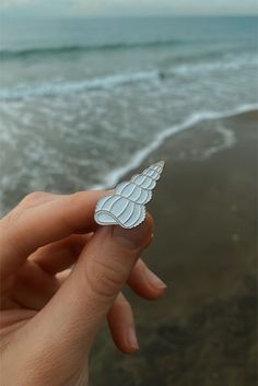 a person is holding a small white object in their hand near the water's edge